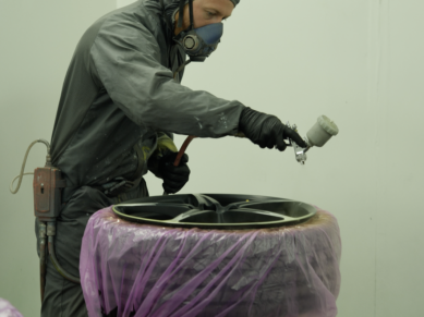 Painter in a respirator spraying an alloy wheel