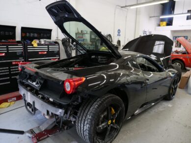 Black Ferrari in the workshop with the engine cover open
