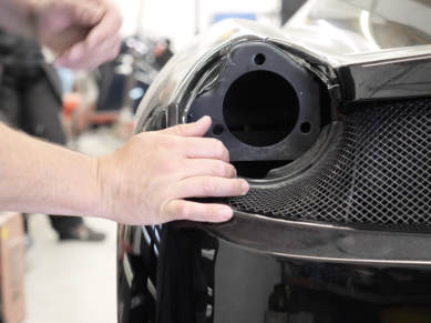 Close-up of a hand checking panel fit around a rear grille