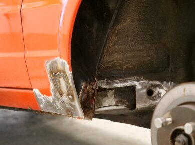 Rusted sill on an orange car before repair