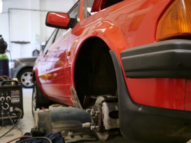 Red car with the rear wheel removed for wheel arch repair