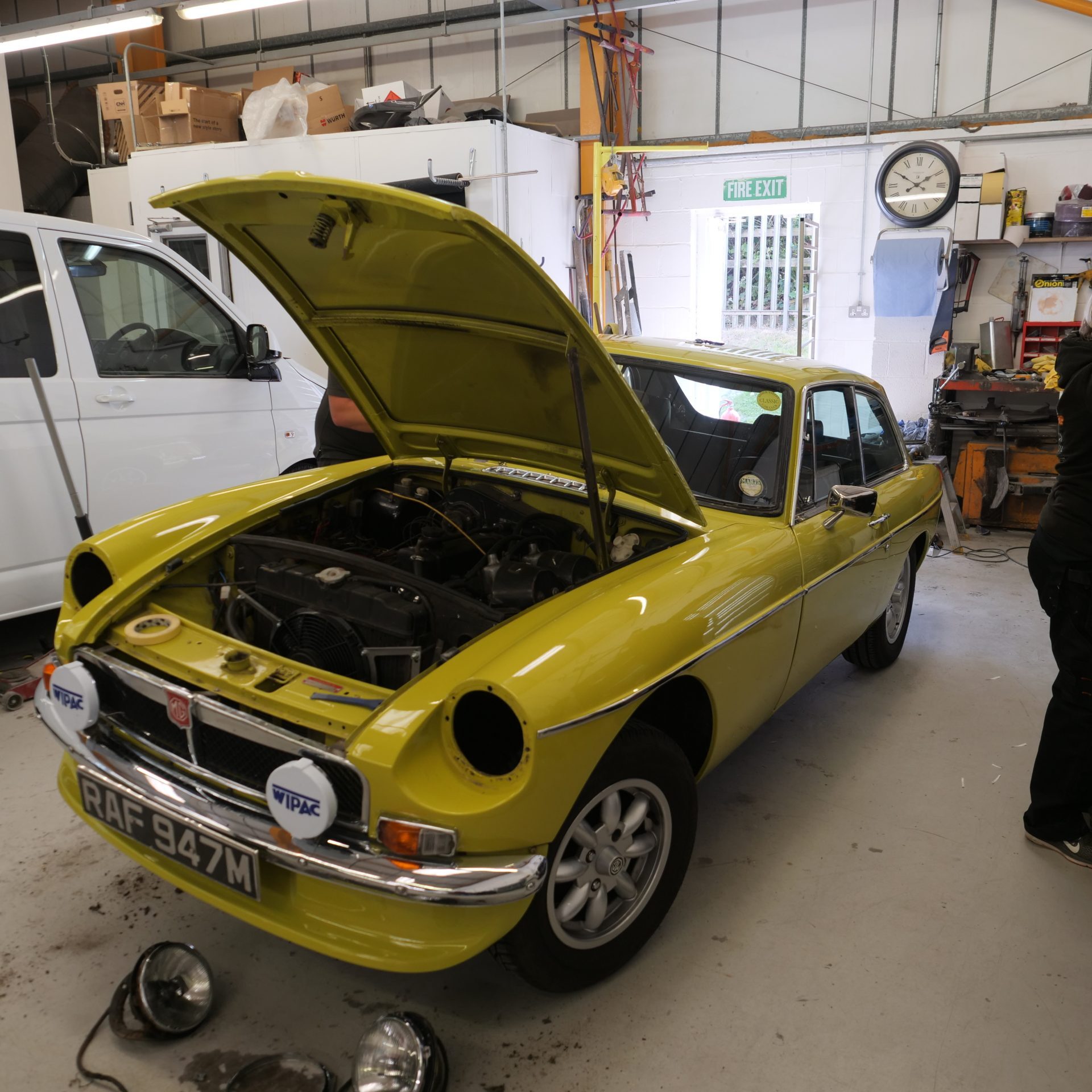 Yellow classic MGB GT in the workshop with the bonnet up